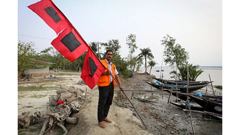 Catherine Davison Sabastin Bachar, team leader of P for Chila village, shows the three-tiered flag system which is displayed in the village square (Credit: Catherine Davison)