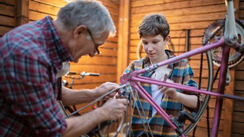 A grandfather and grandson restore an old bike together.