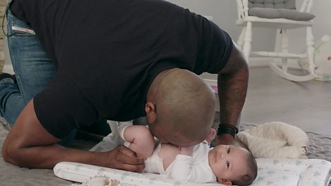 A dad blowing a raspberry on his little girl's tummy.