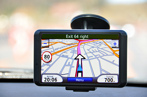 A satellite navigation system attached to the inside of a car windscreen, showing a planned route on a map.