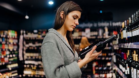 A person examines a wine label in a shop