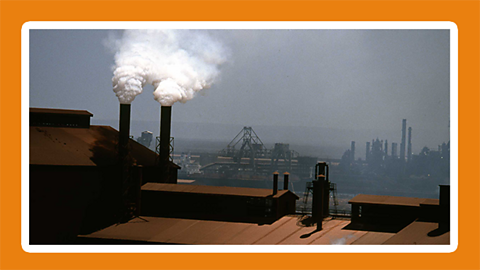 View of a factory with smoke polluting the air with more factories in the distance