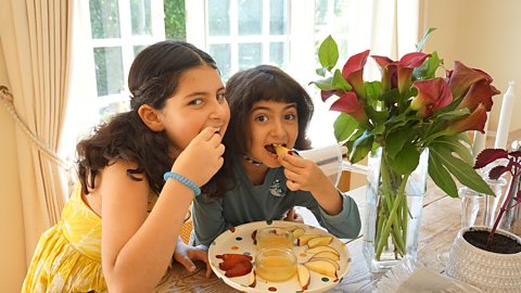 Karen Cinnamon's 2 daughters eating from a ceremonial plate of apple slices.