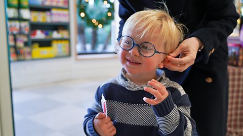 Young mother choosing prescription glasses for her blonde baby boy