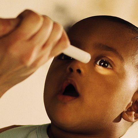 Ophthalmologist giving eye exam to small baby