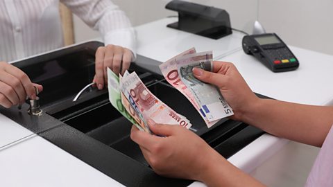 A person at a currency exchange window counting euro notes