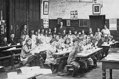 Children eating school meals in their classroom, c.1907.