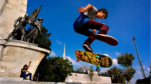 A boy leaps through the air on a skateboard