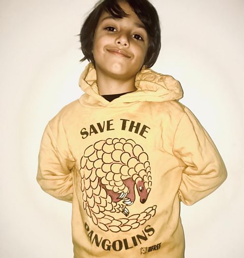 Leo smiles in front of a white wall wearing his Save The Sea Lions jumper