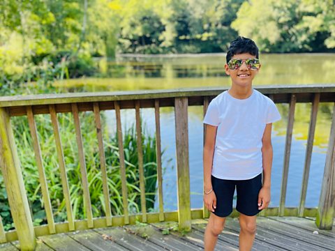 Shaan stands before a lake and smiles for a picture