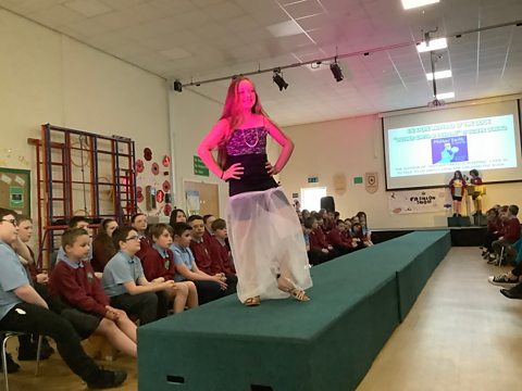 The students show off their fashion show with recycled materials on a runway