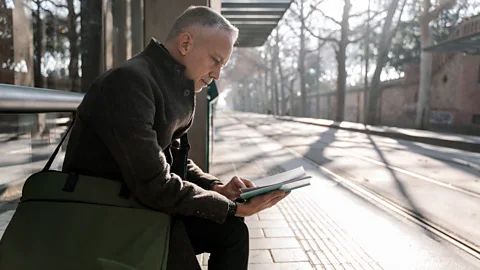 Getty Images Man reading book while commuting