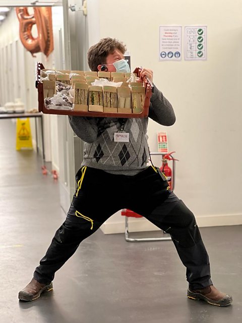 Ben is carrying a big tray of sandwiches.