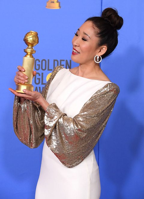 A picture of actor Sandra Oh holding a Golden Globe award.