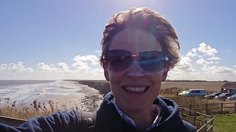 A photograph of Helen Young smiling with a beach in the background