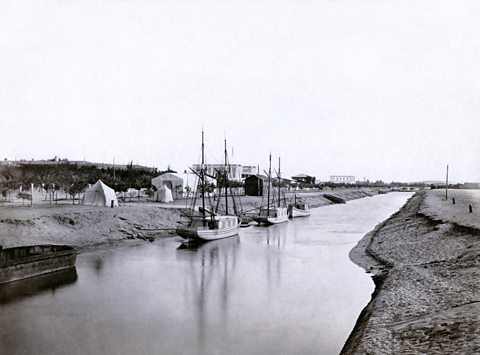 Three ships sail in the Suez Canal in the late 1800s.