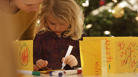 A little girl and her mum making Christmas cards.