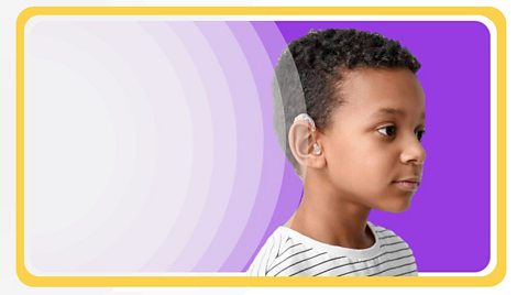 Boy with hearing aid against a coloured background.