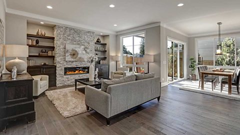 Living room interior in grey and brown colours, grey sofa, dark hardwood floors.