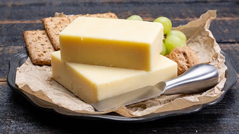 Budget cheeseboards Cheddar on a plate with crackers and grapes