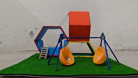 
                    Model of playground equipment including swings made from a bisected ping pong ball and a climbing frame made from cardboard hexagons.
                  