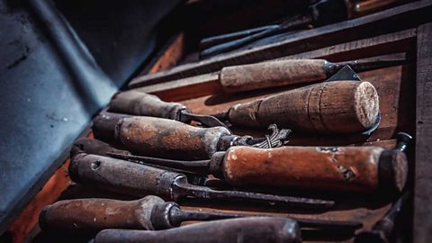 A box of old worn chisels with wooden handles