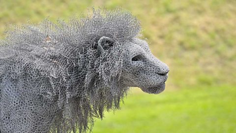 Detailed sculpture of a male lion's head, neck and shoulders in profile