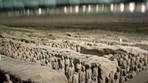 A photograph of the terracotta army. Stone figures standing in rows