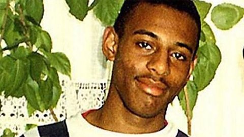 A photograph of Stephen Lawrence standing in front of a plant