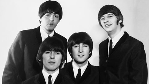 A black and white picture of pop band The Beatles wearing dark suits and ties.