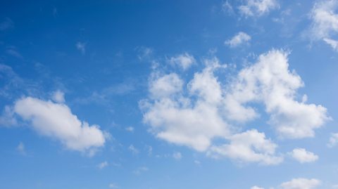 A blue sky with a few fluffy white clouds.