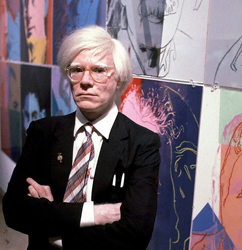 A photograph of Andy Warhol with his art. 