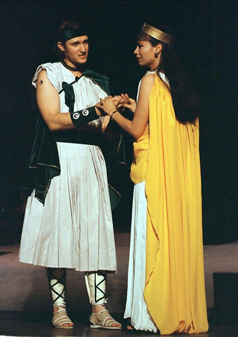 An American actor in a white tunic as Lysander and a Vietnamese actress in a long yellow cloak with a golden hairband as Hermia