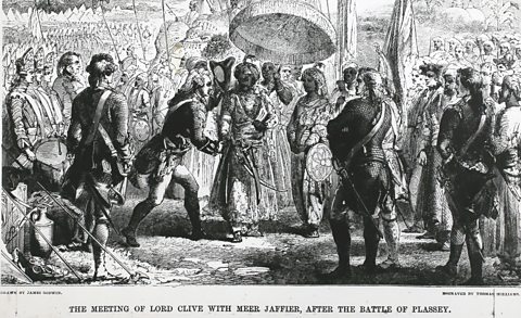 A black and white image of a man dressed in traditional 16th century English army uniform shaking hands with an Indian man in traditional dress. They are surrounded by an army.