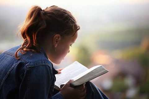 A young woman sat on a step reading the bible and learning about the 12 disciples.