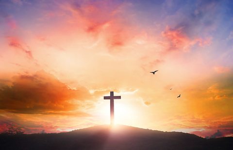 The silhouette of a cross on a hill.