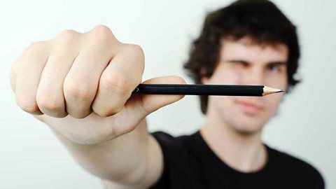 A man holding out a pencil for perspective