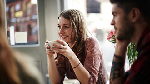 A young female teacher is pictured drinking a hot drink with colleagues in a staff room.