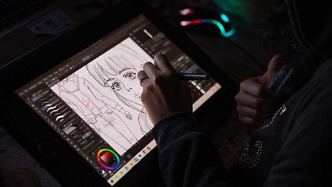 A pair of hands drawing a cartoon face and torso on a tablet