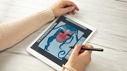 A pair of hands drawing a cartoon face on a tablet