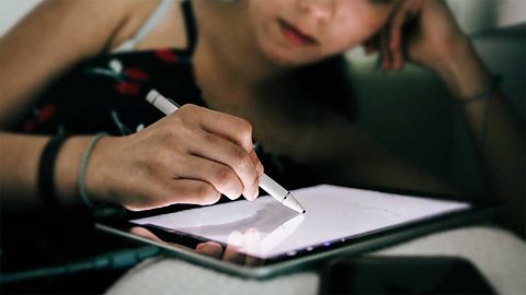 Closeup of a woman's hand drawing on a tablet with a stylus