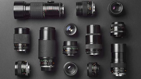 A collection of thirteen black camera lenses all different sizes