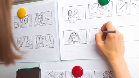 A hand drawing a storyboard in pencil