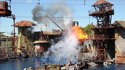 Industrial port with fire and smoke erupting from the dockside