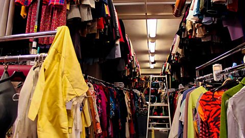 Rows of clothes on rails and a ladder