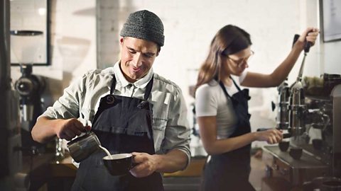 Baristas in aprons preparing coffee in a coffee shop