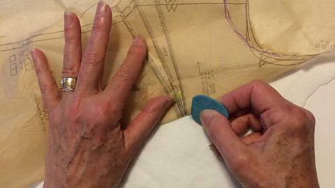 Hands working fabric with a specialist tool