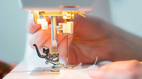 Closeup of a sewing machine sewing some white fabric