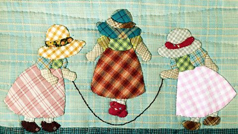 Quilt decorated with design of three girls playing with a skipping rope