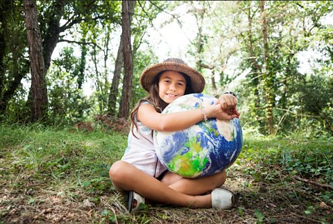 A young girl hugs a model of the Earth.